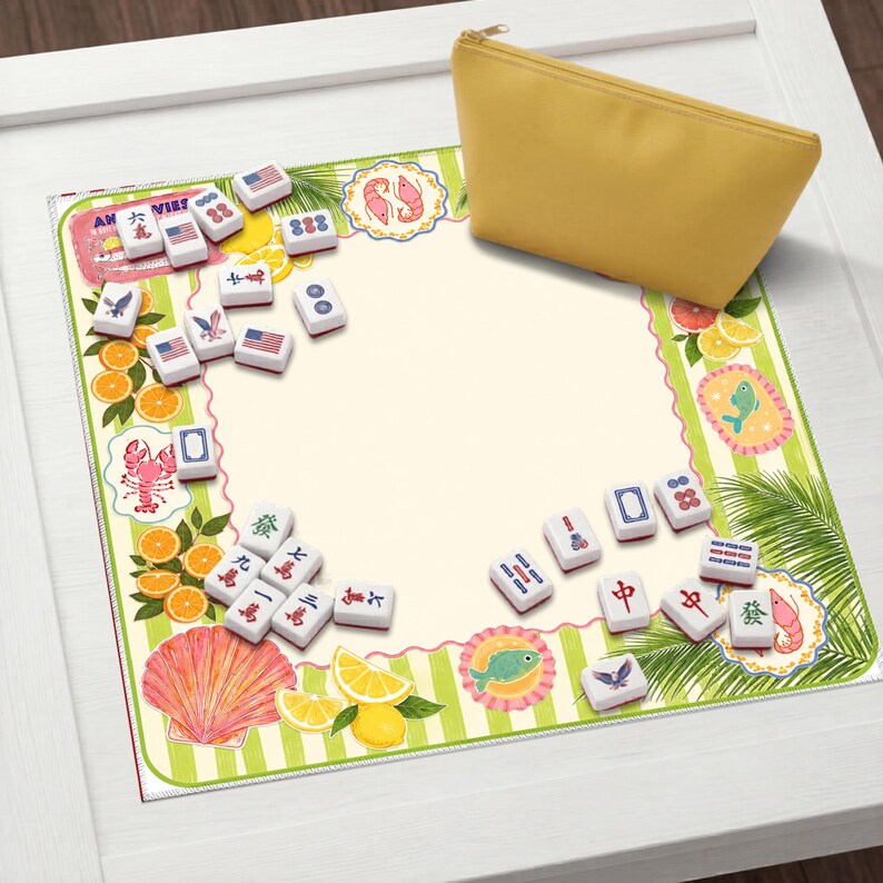 May include: A yellow zippered pouch rests on a decorative mat with a tropical theme. The mat features illustrations of oranges, lemons, and seafood, along with Mahjong tiles. The tiles display various symbols and numbers.