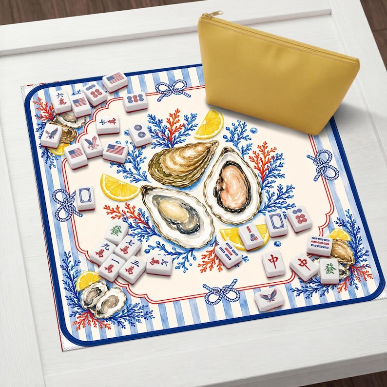 May include: A decorative mahjong set with tiles featuring American flag designs, oysters, and lemon slices. The set includes a yellow zippered pouch and is set on a blue and white striped mat.