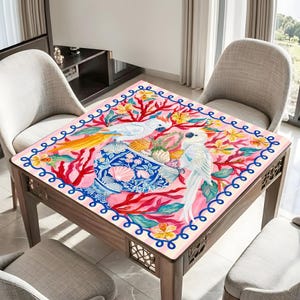 May include: A square wooden table with a painted top featuring two white cockatoos, a blue vase, and coral-like branches on a pink background. The table has a decorative border and is surrounded by chairs.