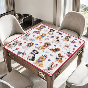 May include: A square tablecloth featuring a repeating pattern of various dog breeds wearing patriotic accessories like red, white, and blue bandanas and hats, interspersed with American flags, fireworks, and stars on a white background.