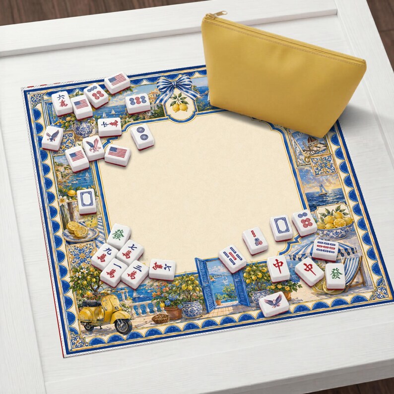 May include: A decorative Mahjong set with tiles featuring American flag designs and other symbols. The set is arranged on a patterned mat with a yellow pouch. The mat has a blue border with a coastal scene.