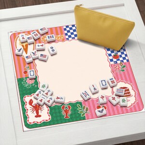 May include: A yellow zippered pouch rests on a colorful mat with a pink and green border. The mat features illustrations of food, flags, and Mahjong tiles. The tiles are white with black symbols. The mat is on a white surface.