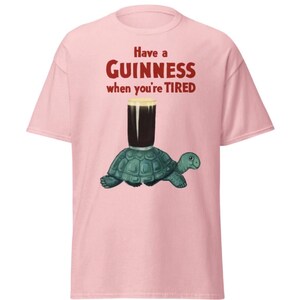 May include: Pink t-shirt with the text "Have a GUINNESS when you're TIRED" in red. A cartoon turtle is carrying a glass of Guinness.