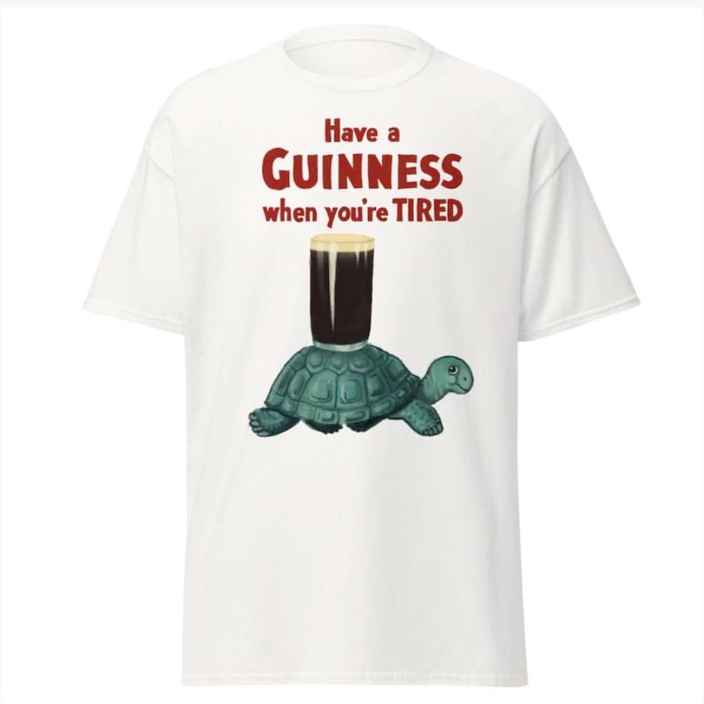 May include: White t-shirt with a graphic of a turtle carrying a glass of Guinness beer. The text on the shirt reads "Have a GUINNESS when you're TIRED."