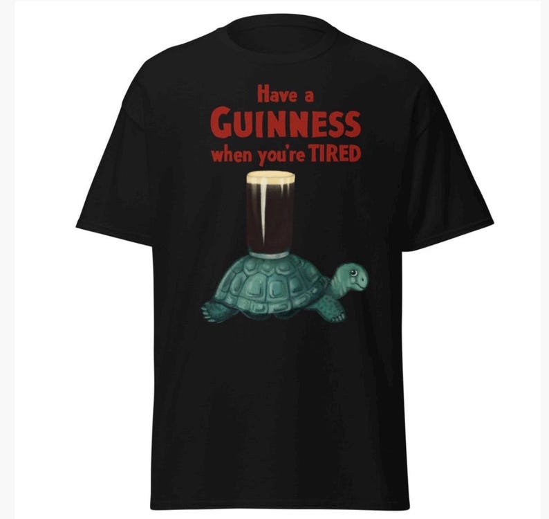 May include: Black t-shirt with a graphic of a turtle carrying a glass of Guinness beer. The text on the shirt reads "Have a Guinness when you're tired."