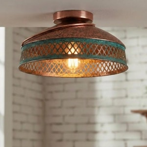 May include: A ceiling light with a copper finish and a teal band. The light has a decorative metal mesh shade and a visible Edison-style bulb. The fixture is mounted on a white ceiling. The light is a decorative home decor item.