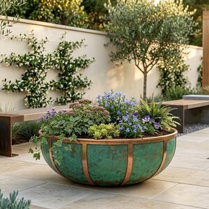 May include: A lush garden scene featuring a large, green and copper-banded planter overflowing with colorful flowers and greenery. A geometric dark gray planter with a succulent plant is on the left. The scene includes benches, trees, and a pergola.