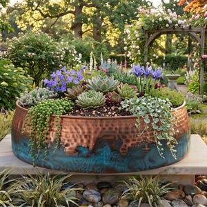 Peut inclure: Une grande jardinière ronde en cuivre martelé avec une finition patinée bleu sarcelle à la base. La jardinière est remplie d'une variété de plantes succulentes vertes, dont des colliers de perles retombants, et de fleurs violettes.