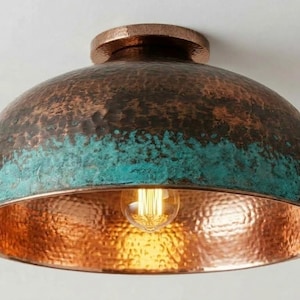May include: A copper ceiling light fixture with a dome-shaped shade. The shade has a hammered texture and a gradient of colors, transitioning from copper to teal. An Edison-style bulb is visible.