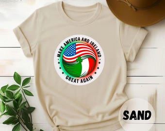May include: Sand-colored t-shirt featuring a circular graphic with the text "MAKE AMERICA AND IRELAND GREAT AGAIN." The graphic combines the American and Irish flags. A brown hat is visible in the background.