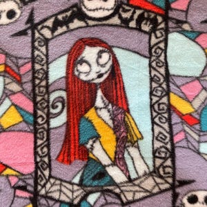 Puede incluir: Una tela colorida con un patr&oacute;n repetido de Jack Skellington y Sally de Pesadilla Antes de Navidad. La tela presenta un fondo morado con acentos negros, blancos, rojos, amarillos, azules y rosas.