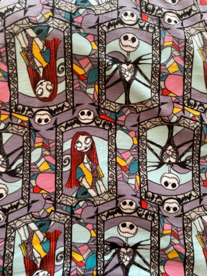 Puede incluir: Una tela colorida con un patr&oacute;n repetitivo de ventanas de vidrieras con Jack Skellington y Sally de Pesadilla Antes de Navidad. Las ventanas est&aacute;n delineadas en negro y tienen un dise&ntilde;o de telara&ntilde;a.