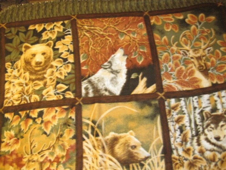 Pode incluir: Uma colcha de retalhos com um tema de floresta. A colcha apresenta imagens de ursos, lobos, veados e &aacute;rvores em tons de marrom, verde e amarelo.