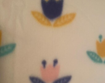 Pequeños capullos coloridos se encuentran dispersos por todas partes sobre una colcha de polar de dos capas de color rosa y blanco.