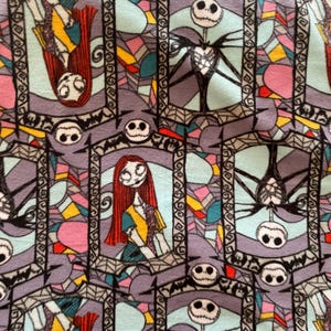 Puede incluir: Un patr&oacute;n repetido de ventanas de vidrieras con Jack Skellington y Sally de Pesadilla antes de Navidad. Las ventanas son en tonos de azul, rosa, amarillo y gris.