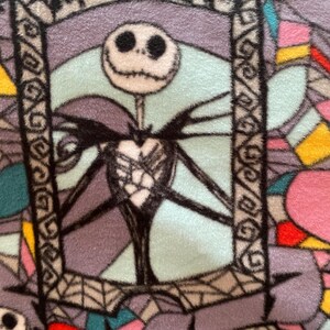 Puede incluir: Un primer plano de una tela con un patr&oacute;n de vitral que presenta a Jack Skellington de Pesadilla antes de Navidad. La tela es una mezcla de morado, azul, rosa, amarillo y rojo.
