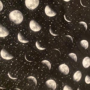 May include: Black fabric with a white moon phase pattern. The fabric is covered in small white dots, resembling stars.