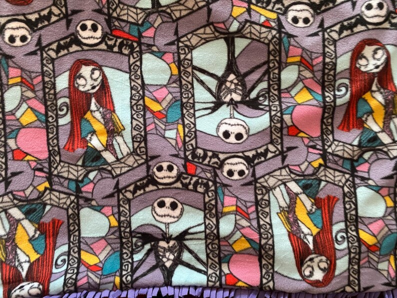 Puede incluir: Una tela colorida con un patr&oacute;n repetitivo de ventanas de vidrieras con Jack Skellington y Sally de Pesadilla antes de Navidad. Las ventanas est&aacute;n delineadas en negro y tienen un fondo morado.