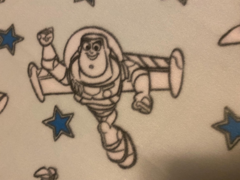 May include: A black and white illustration of a cartoon character flying a spaceship. The character is wearing a space suit and has a big smile. The background is light blue with white stars.