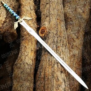 May include: A silver sword with a detailed hilt featuring gold accents and a blue and green wrapped handle. The blade has etched markings and a decorative emblem near the hilt. The sword is displayed against a textured brown background.