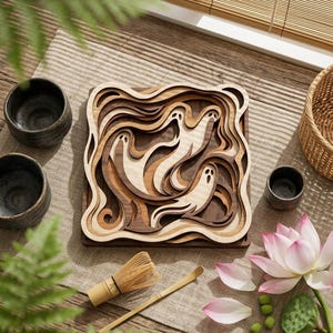May include: A square wooden wall art piece featuring layered, wavy cutouts that form three ghost figures. The design uses varying shades of natural wood, from light beige to dark brown, creating a dimensional, topographic effect with smooth, flowing curves.