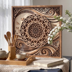 May include: A square, multi-layered wooden wall art piece featuring a central mandala design surrounded by swirling patterns and small bird silhouettes. The artwork uses contrasting light and dark wood tones to create depth and intricate detail.