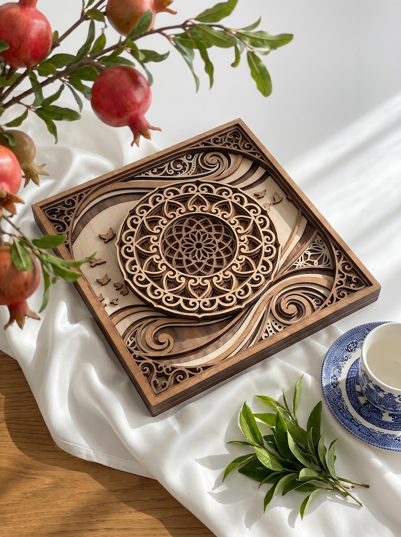 May include: A square, multi-layered wooden wall art piece featuring intricate laser-cut patterns. The design includes a central circular mandala motif surrounded by flowing, wave-like shapes and small bird silhouettes, crafted from light and dark wood.