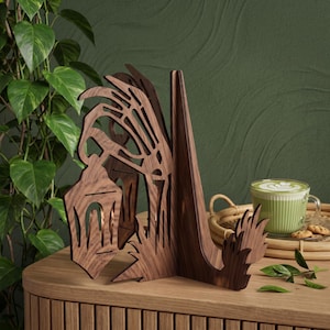 May include: A dark brown wooden bookend featuring a skeletal hand reaching down to hold a lantern. The intricate cutout design displays a vertical support structure and a base, crafted from wood with a visible grain pattern and smooth finish.