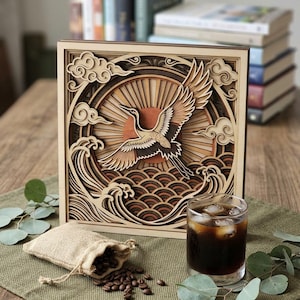 May include: A square, multi-layered wooden wall art piece featuring a laser-cut design of a crane in flight against a sunburst background, stylized clouds, and ocean waves. The artwork uses various shades of natural wood to create depth and texture.