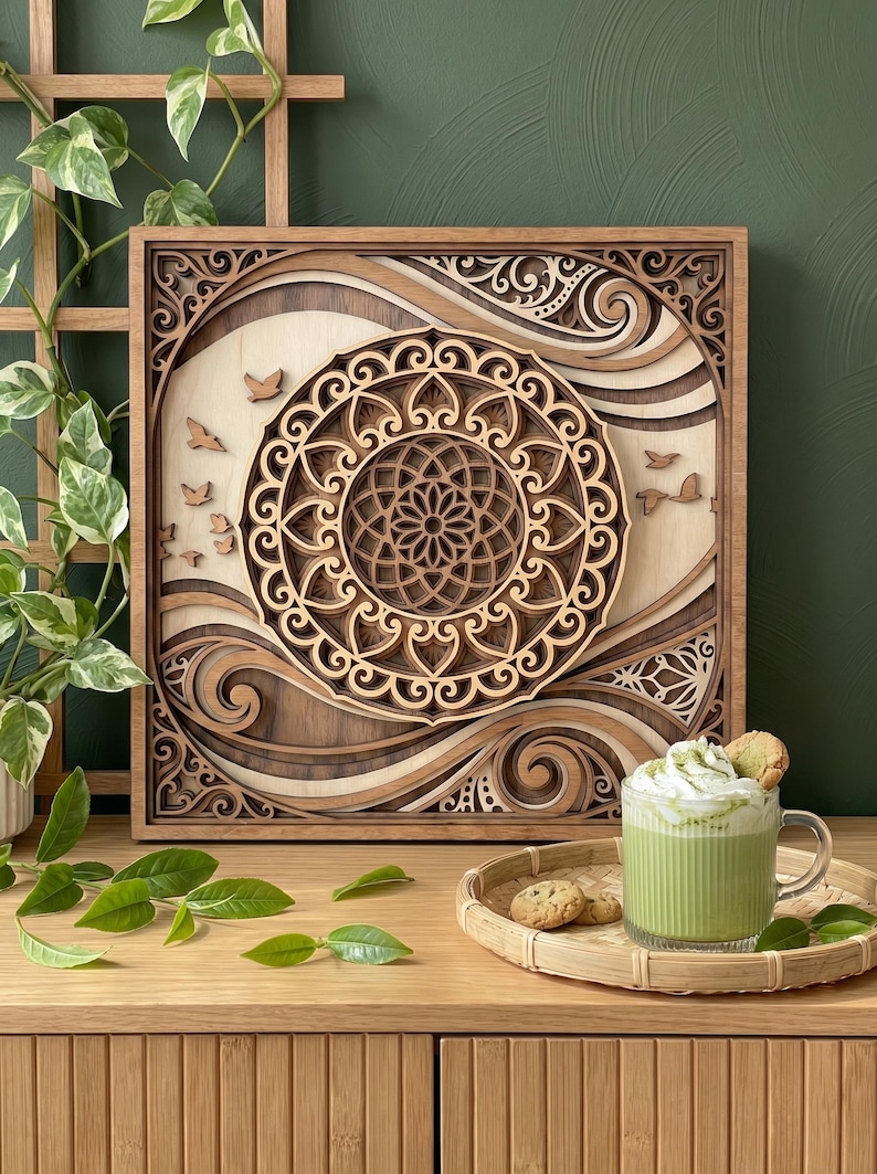 May include: A square wooden wall art piece featuring layered, laser-cut mandala patterns in light and dark wood tones. The design includes swirling wave motifs and small bird silhouettes. The artwork is framed in a natural wood border.