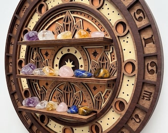 May include: A circular wooden wall shelf featuring three horizontal tiers for display. The frame is carved with twelve zodiac symbols. The background displays layered wood cutouts of crystals and stars. Various polished gemstones sit on the shelves.