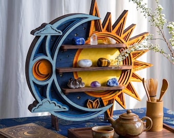 May include: A layered wooden wall shelf shaped like a sun and moon, featuring three horizontal shelves holding various crystals. The design includes blue, yellow, and orange tones with cut-out star and cloud details, standing on a wooden base.