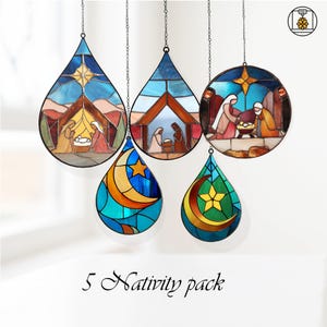 Peut inclure: Cinq ornements en vitrail représentant des scènes de la Nativité et des motifs célestes. Les ornements ont des formes de goutte d'eau et circulaires, avec une variété de couleurs, dont le bleu, l'orange et le vert. Chaque pièce est suspendue par une chaîne, avec le texte "5 Nativity pack" en bas.