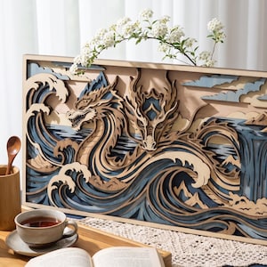 Pode incluir: Uma peça de arte de parede retangular de madeira multicamadas com um design detalhado de dragão integrado com ondas oceânicas estilizadas, uma cachoeira e picos de montanhas. A obra utiliza vários tons de azul, bege e madeira natural.