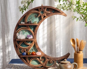 May include: A crescent moon-shaped wooden wall shelf with three horizontal tiers holding various polished crystals. The shelf features intricate laser-cut star and swirl patterns against a teal background, crafted from dark brown wood.