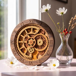 Op de afbeelding: Een ronde houten klok met een donkerbruine buitenrand met gegraveerde Romeinse cijfers en een ingewikkeld, meerlaags intern tandwielmechanisme in verschillende lichte en middelbruine houttinten, tentoongesteld naast een heldere glazen vaas.