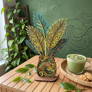 May include: A multi-layered wooden decorative object featuring a vase base with wave patterns and five upright feather-shaped cutouts. The piece is constructed from stacked wood layers in shades of teal, yellow, dark blue, and natural brown wood tones.