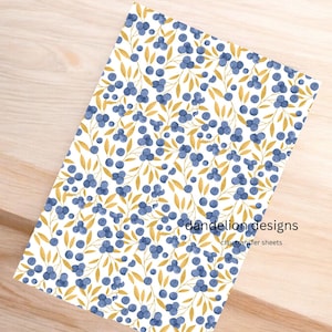 May include: A rectangular sheet with a repeating pattern of blue berries and gold leaves on a white background. The text "dandelion designs" and "clay transfer sheets" is printed on the sheet.