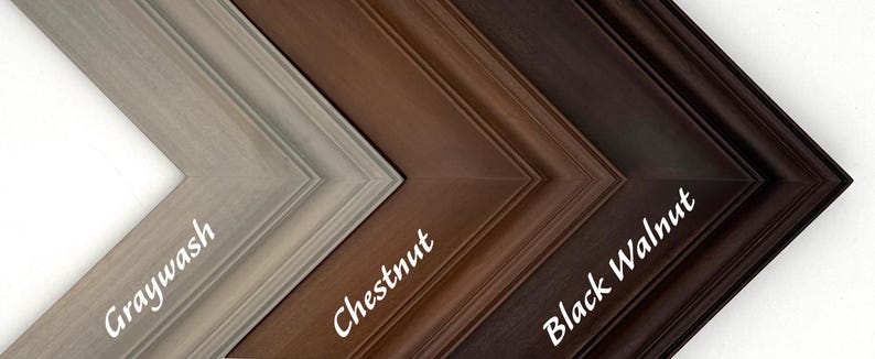 May include: Close-up of four wooden picture frame samples in a diagonal arrangement. The frames are labeled "Graywash", "Chestnut", and "Black Walnut". The frames have a beveled edge and are in shades of gray, brown, and black.