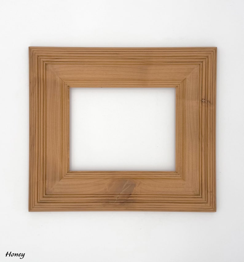May include: A square wooden picture frame with a honey-colored finish. The frame has a layered design with a recessed inner edge and a smooth, light-colored interior. The word "Honey" is printed in the bottom left corner.