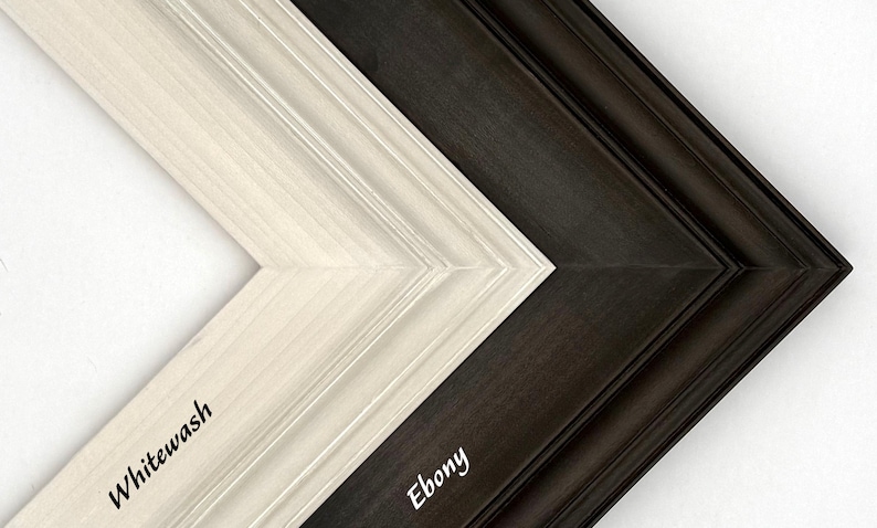 May include: Close-up of two wooden picture frame corners. One is whitewashed, the other is ebony. The whitewash frame has the word "Whitewash" printed on it. The ebony frame has the word "Ebony" printed on it.