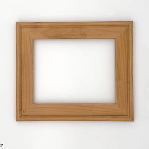 May include: A rectangular wooden picture frame in a warm honey color. The frame has a simple, classic design with a slightly raised border. The frame is empty, with a white background visible through the opening. The word "Honey" is in the bottom left corner.