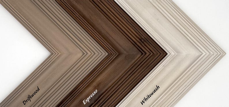 May include: Close-up of three wooden picture frames in different colors: Driftwood, Espresso, and Whitewash. The frames have a textured, grooved design and are angled to show their corners. The names of the colors are written on the frames.