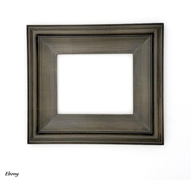 May include: A rectangular ebony-colored picture frame with a white interior. The frame has a layered design and is set against a white background. The word "Ebony" is printed in the lower left corner.
