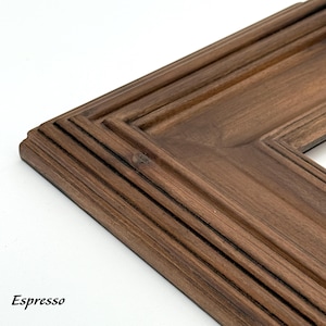 May include: Close-up of a corner of a wooden picture frame with a rich espresso finish. The frame has a layered design with detailed molding and the word "Espresso" in the bottom left corner.