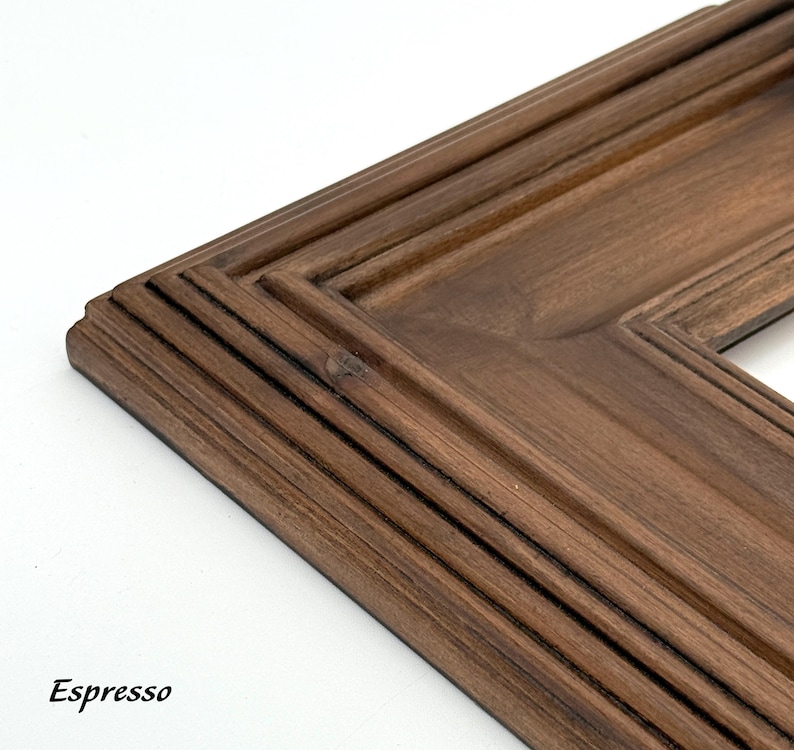 May include: Close-up of a corner of a wooden picture frame with a rich espresso finish. The frame has a layered design with detailed molding and the word "Espresso" in the bottom left corner.