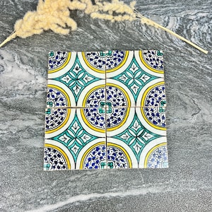 Peut inclure: Quatre carreaux de céramique carrés avec un motif répétitif de motifs bleus, jaunes et turquoise. Les carreaux sont disposés ensemble, présentant un motif décoratif et coloré. Les carreaux sont probablement pour la décoration intérieure.