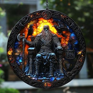 Puede incluir: Obra de arte redonda de vidrieras que representa una figura sentada con una larga barba, sosteniendo un hacha y flanqueada por dos p&aacute;jaros negros. El fondo tiene un dise&ntilde;o de vidrieras colorido con un borde oscuro y ornamentado.