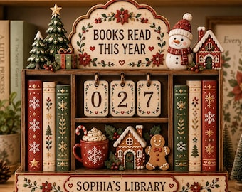 May include: A wooden bookshelf-style tracker with the text "BOOKS READ THIS YEAR" and "SOPHIA'S LIBRARY". It features three hanging number cards showing 027, a red mug with whipped cream, a gingerbread house, a gingerbread person, and Christmas decor.