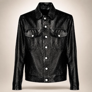 Peut inclure: Une veste noire avec un motif texturé en peau de serpent sur toute la surface. Le vêtement comprend un col pointu, des manches longues avec poignets boutonnés et une fermeture à boutons sur le devant. Deux poches poitrine à rabat boutonné.